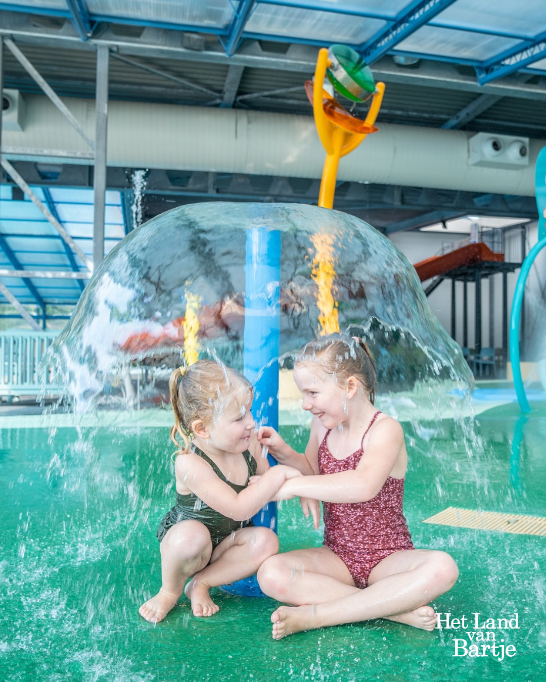 Zwemmen op Land van Bartje met kinderen bij waterspeelplek en sproeiers.