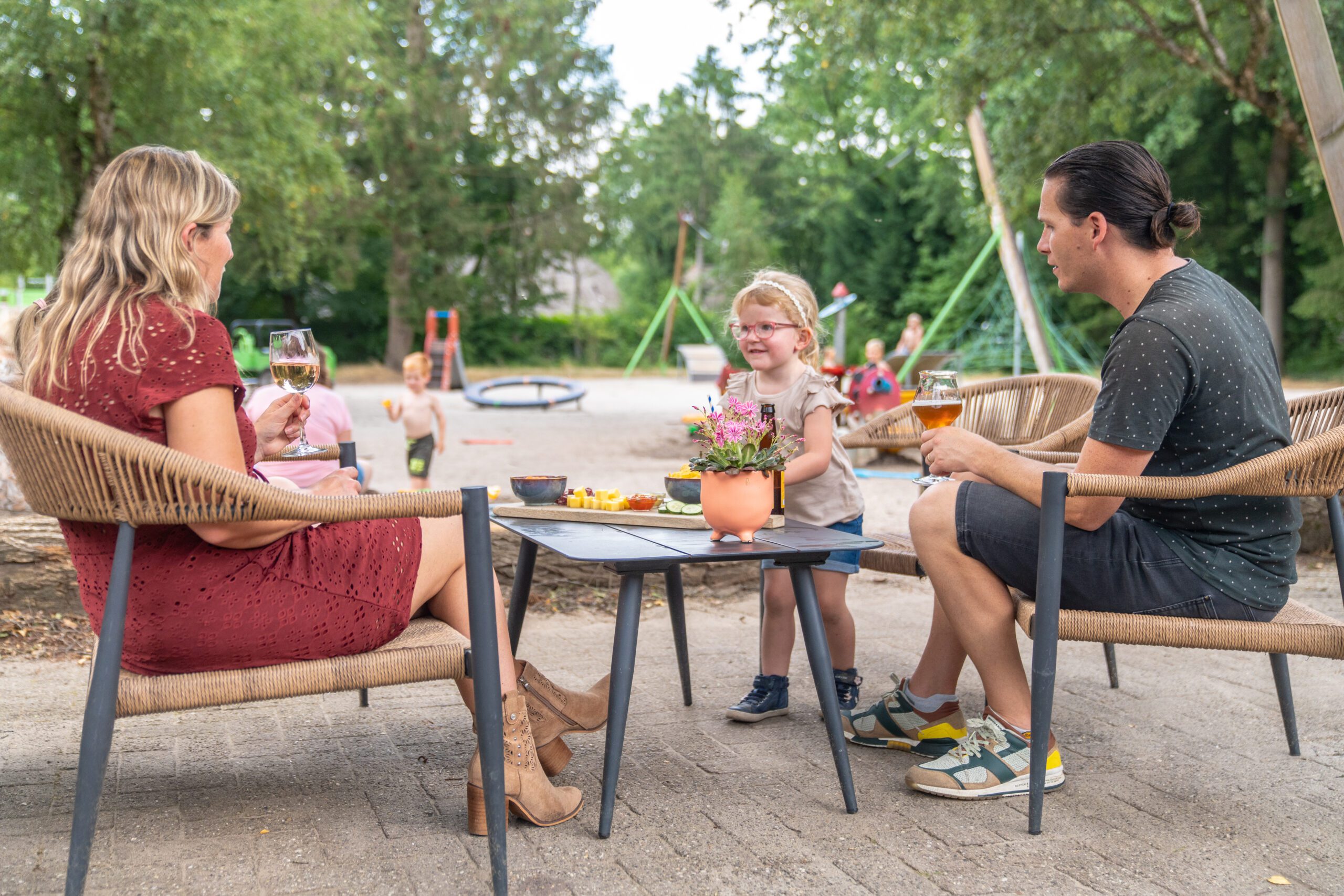 Gezin geniet van eten op het terras van een restaurant op vakantiepark in Drenthe met speeltuin.